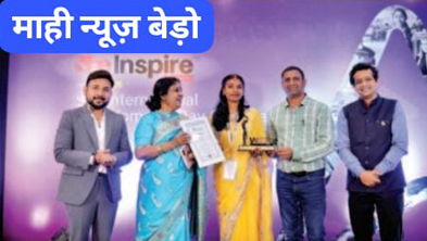 Group of five people on a stage at an awards ceremony; two women in sarees receive a certificate while others stand beside them on a purple backdrop with an 'Inspire' sign nearby.